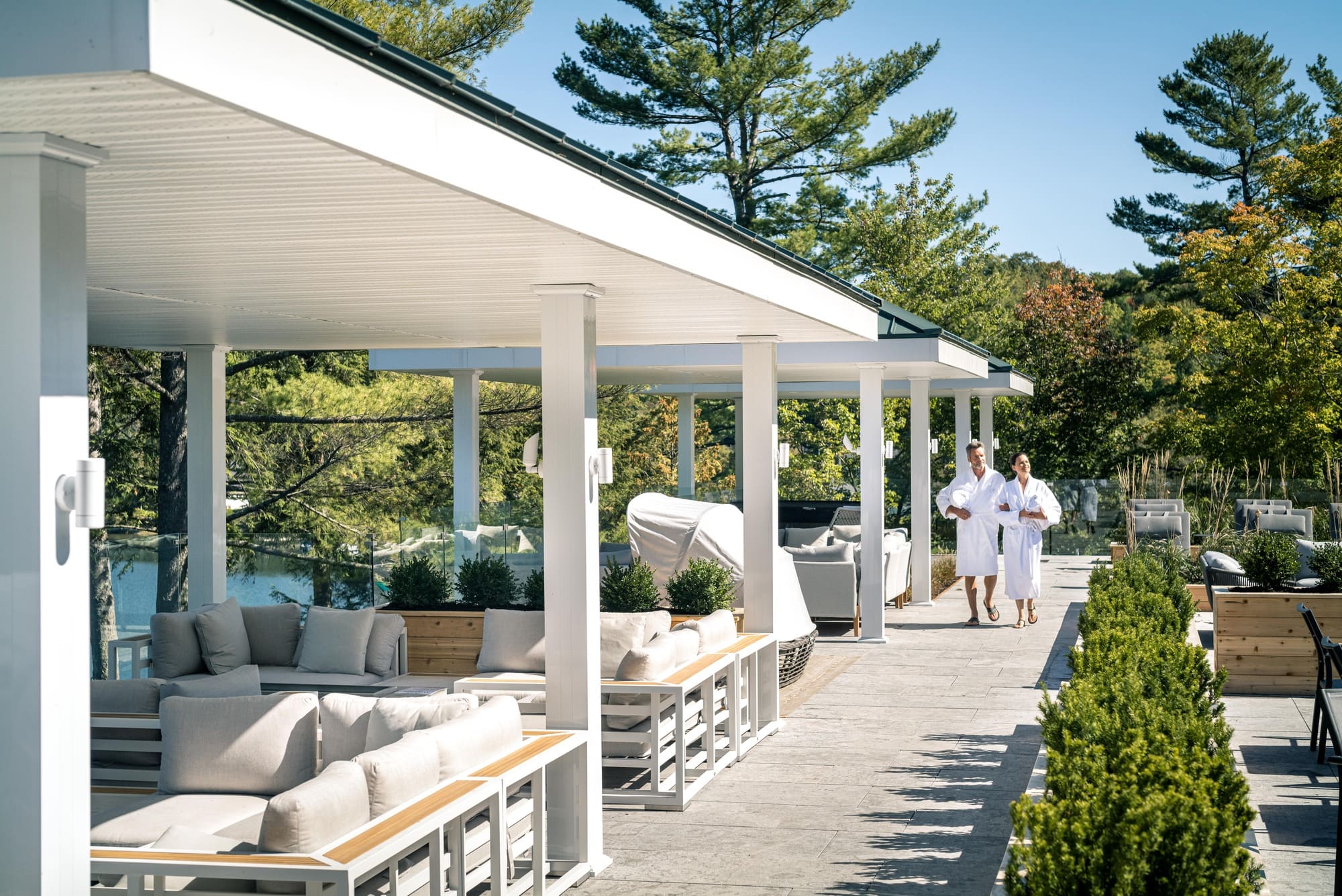 Couple en peignoir marchant sur la terrasse lounge du Ripplecove, hôtel spa au bord du lac en Estrie