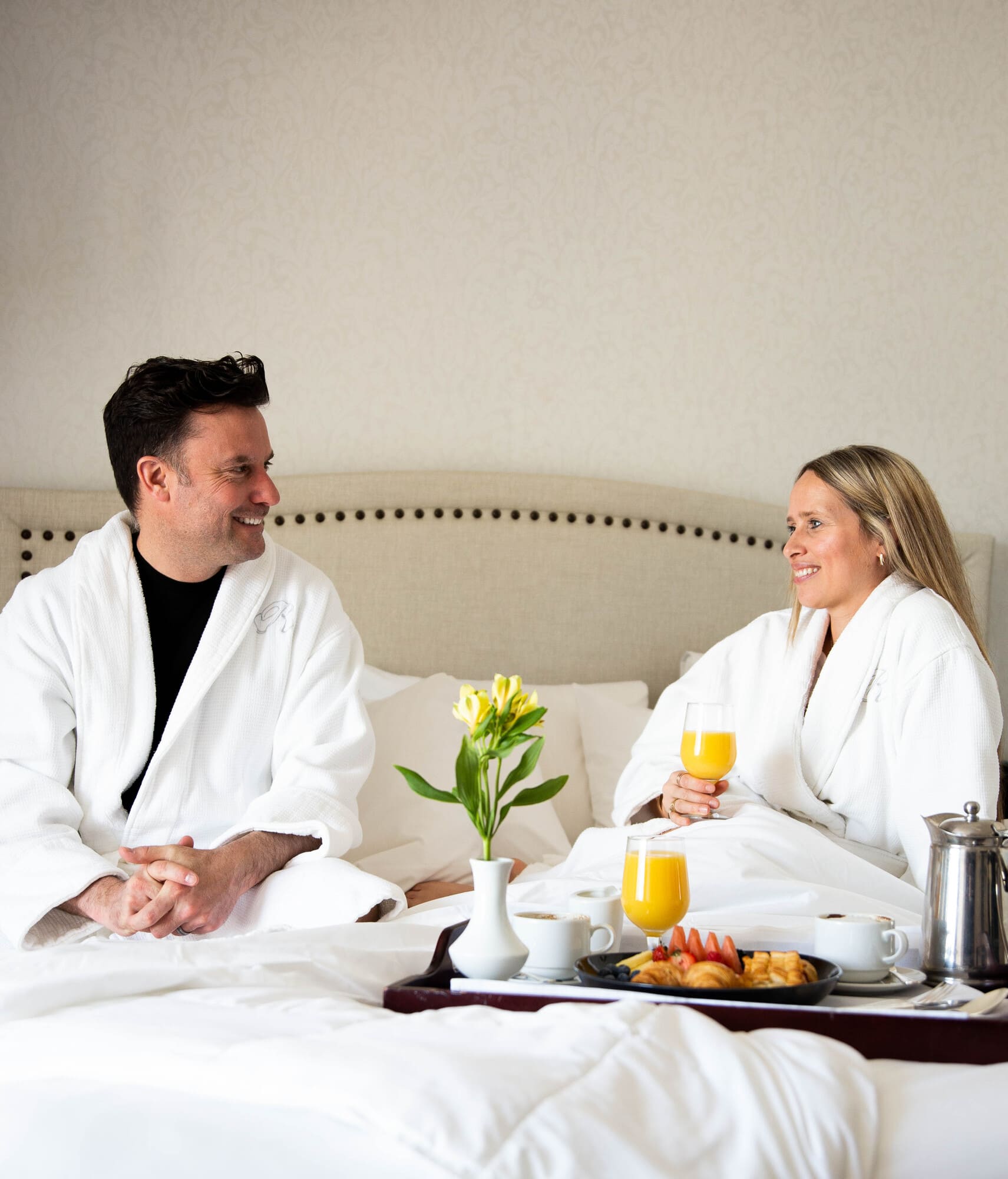 Couple en peignoir savourant un déjeuner au lit dans une chambre de l'hôtel spa du Ripplecove