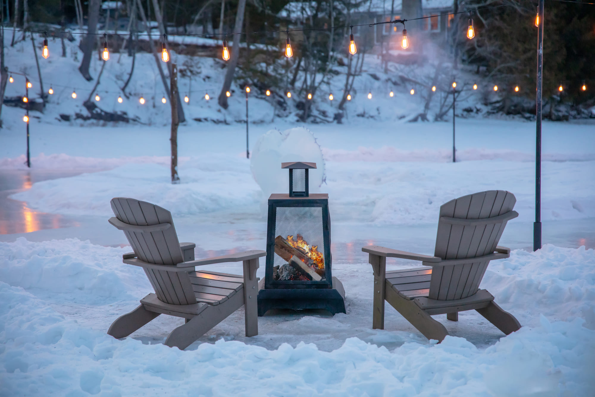 Feu extérieur devant une chaise Adirondack au bord du lac Massawippi en hiver, près de l'hôtel Ripplecove