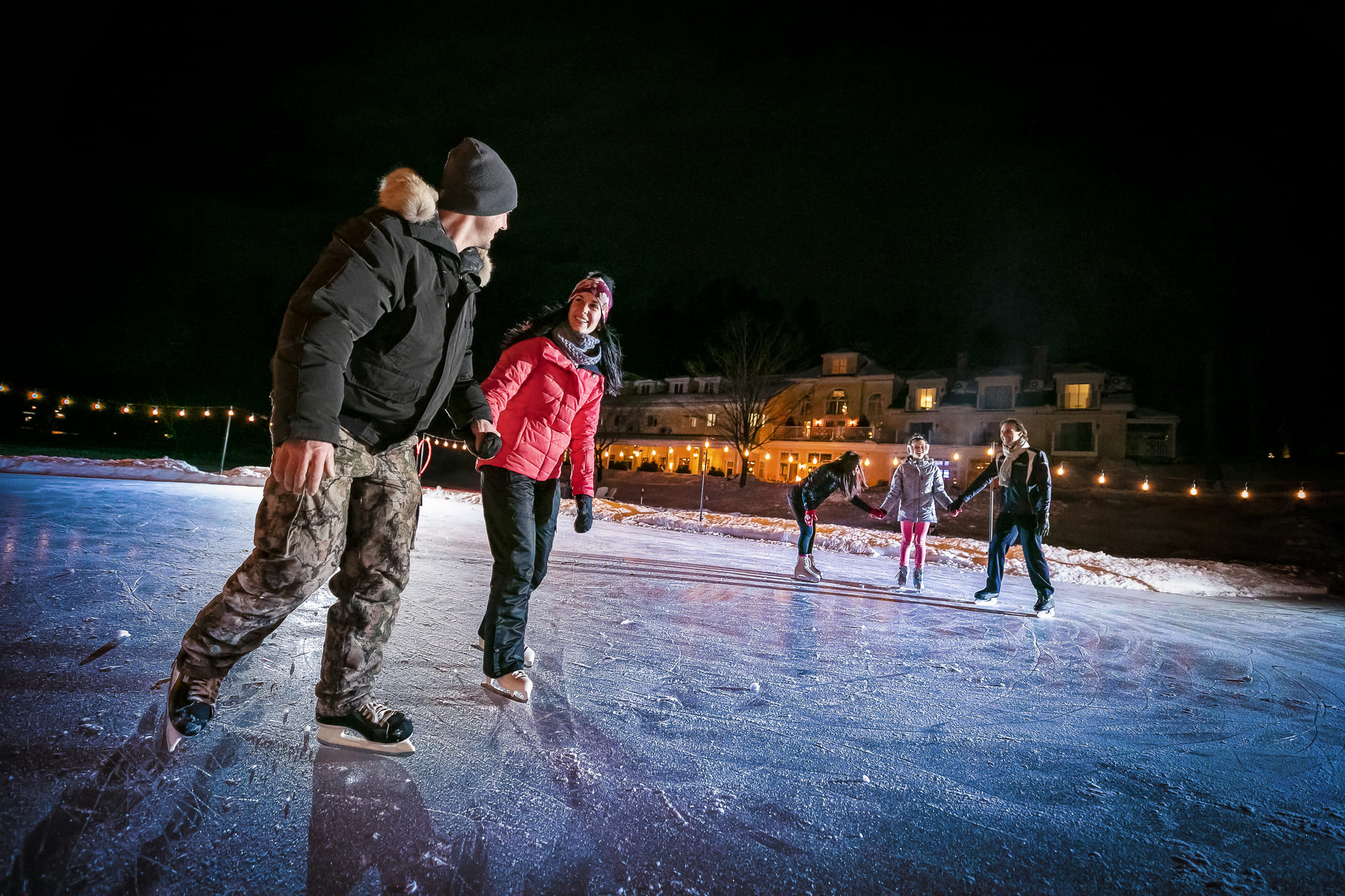 Famille patinant sur le lac Massawippi avec vue sur l'hôtel Ripplecove en Estrie