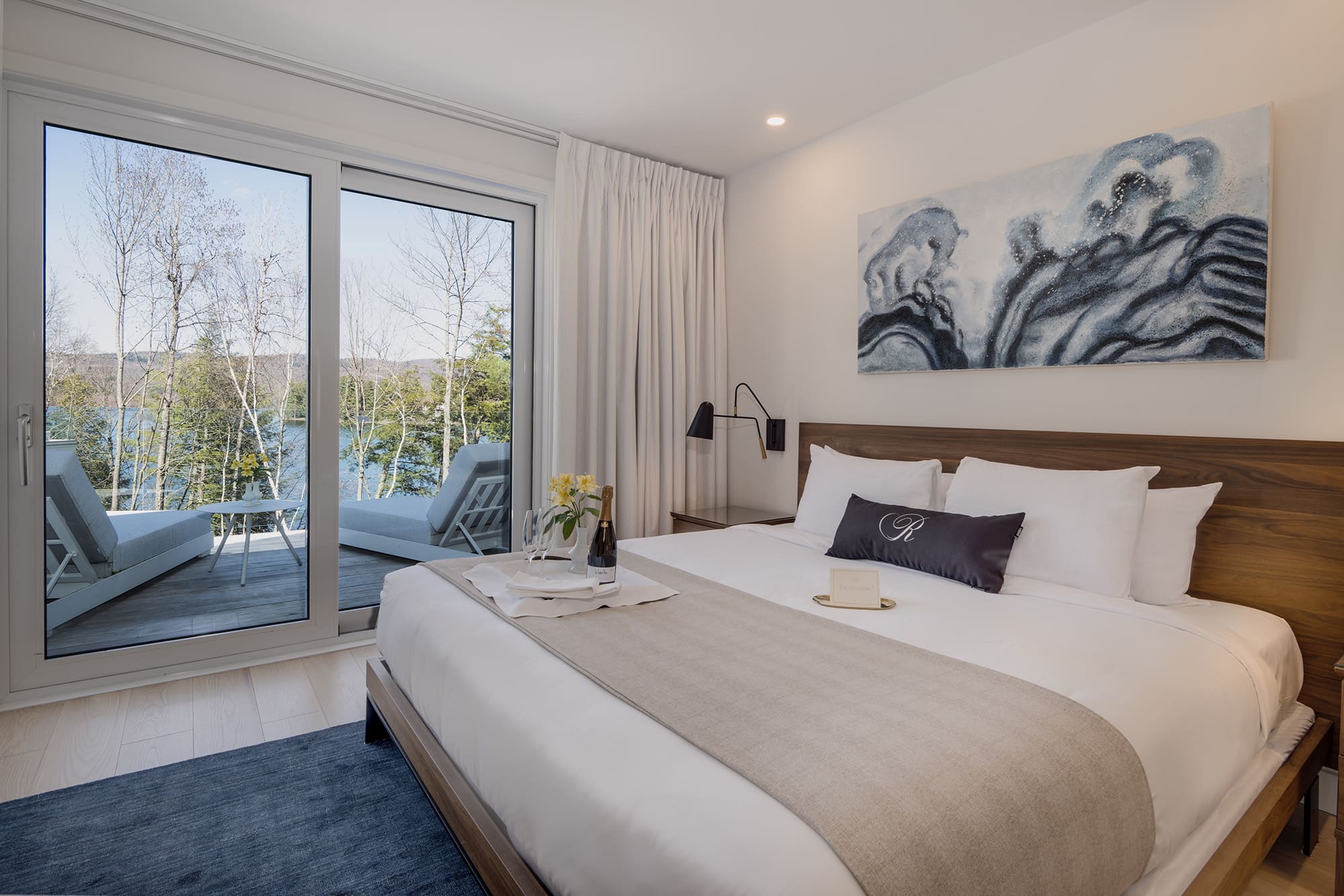 Chambre du Ripplecove Hôtel et Spa avec lit double et grande baie vitrée offrant une vue imprenable sur le lac en Estrie.