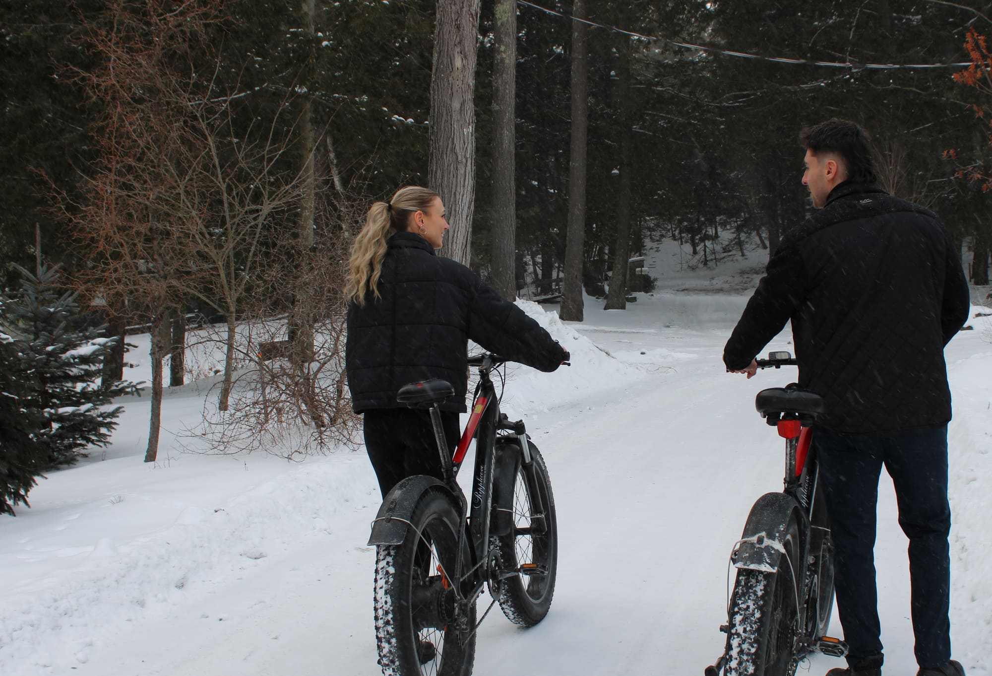 Deux personnes avec leurs vélos à pneus surdimensionnés (fatbikes) sur un sentier enneigé en forêt, lors d’une sortie hivernale dans les Cantons-de-l’Est au Québec.